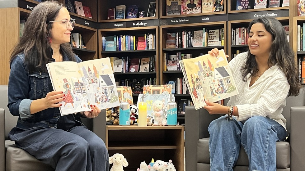 local author and Brown student hold pictures books up as they read aloud to kids